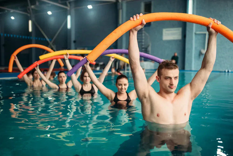 grupa osób ćwiczących aqua aerobik w basenie ze sprzętem