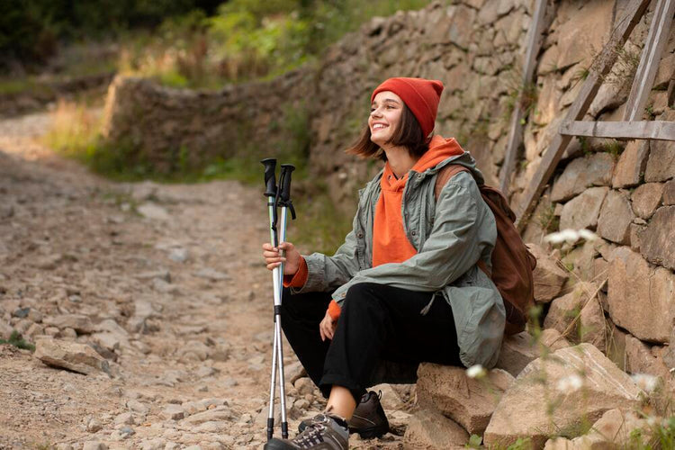 młoda kobieta z kijkami do nordic walking odpoczywa podczas wędrówki