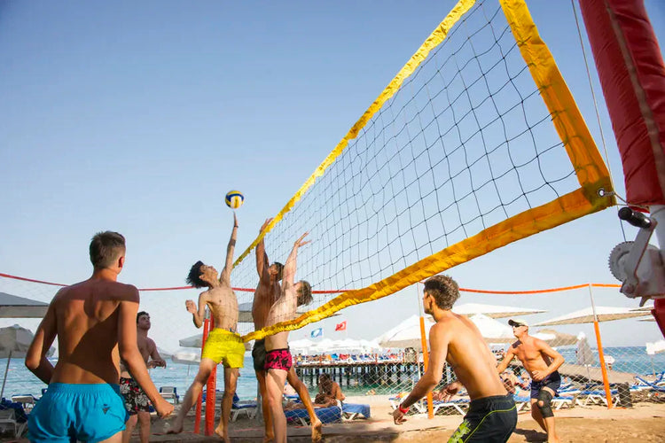 zespół młodych mężczyzn gra w siatkówkę plażową