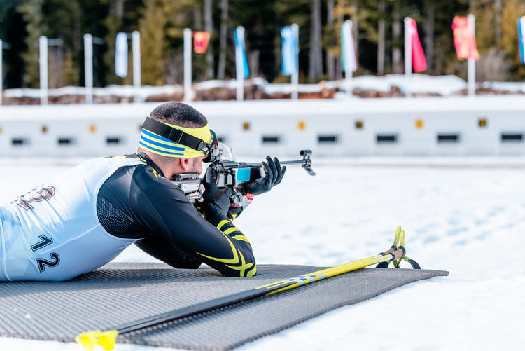 biathlonista oddający strzał z karabinu w zawodach