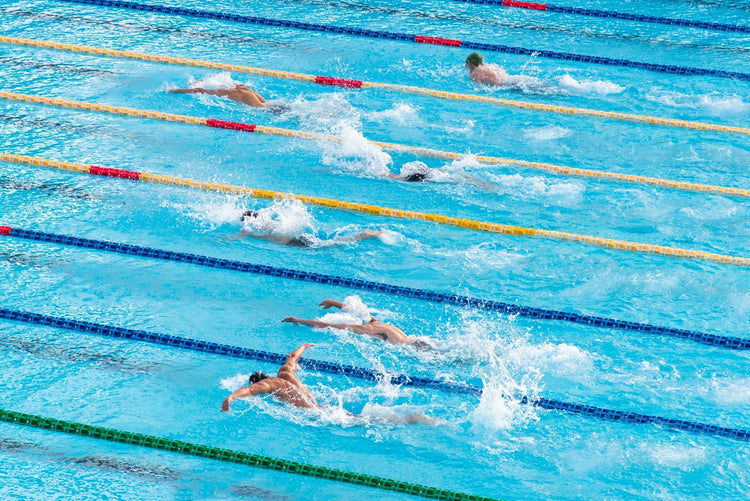 Sportowi pływacy w basenie podczas treningu różnych stylów pływackich, ilustrujący techniki pływania i ich zastosowanie.