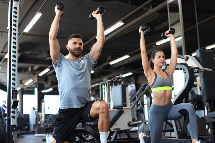 Kobieta i mężczyzna podnoszący hantle, ilustrujący trening wytrzymałościowy rozwijający siłę mięśni, kondycję i ogólną sprawność fizyczną.