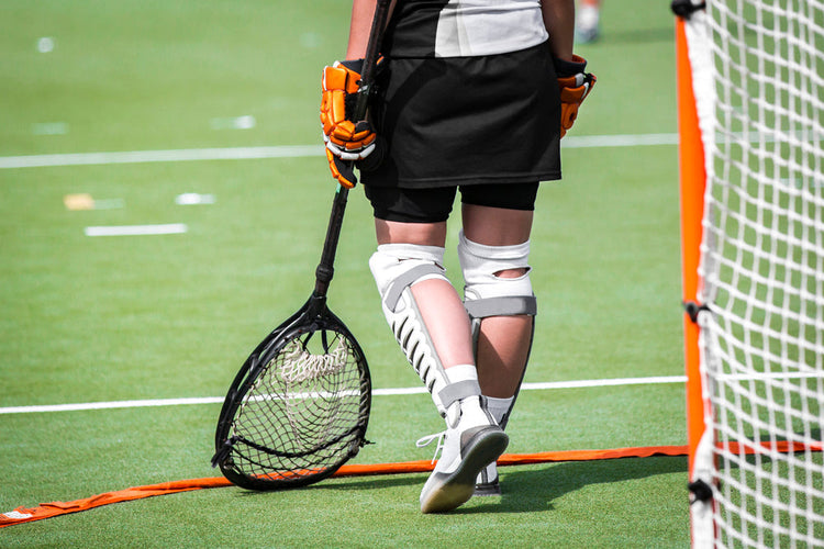 widok na osobę trzymająca kijek do gry w lacrosse ubraną w ochraniacze